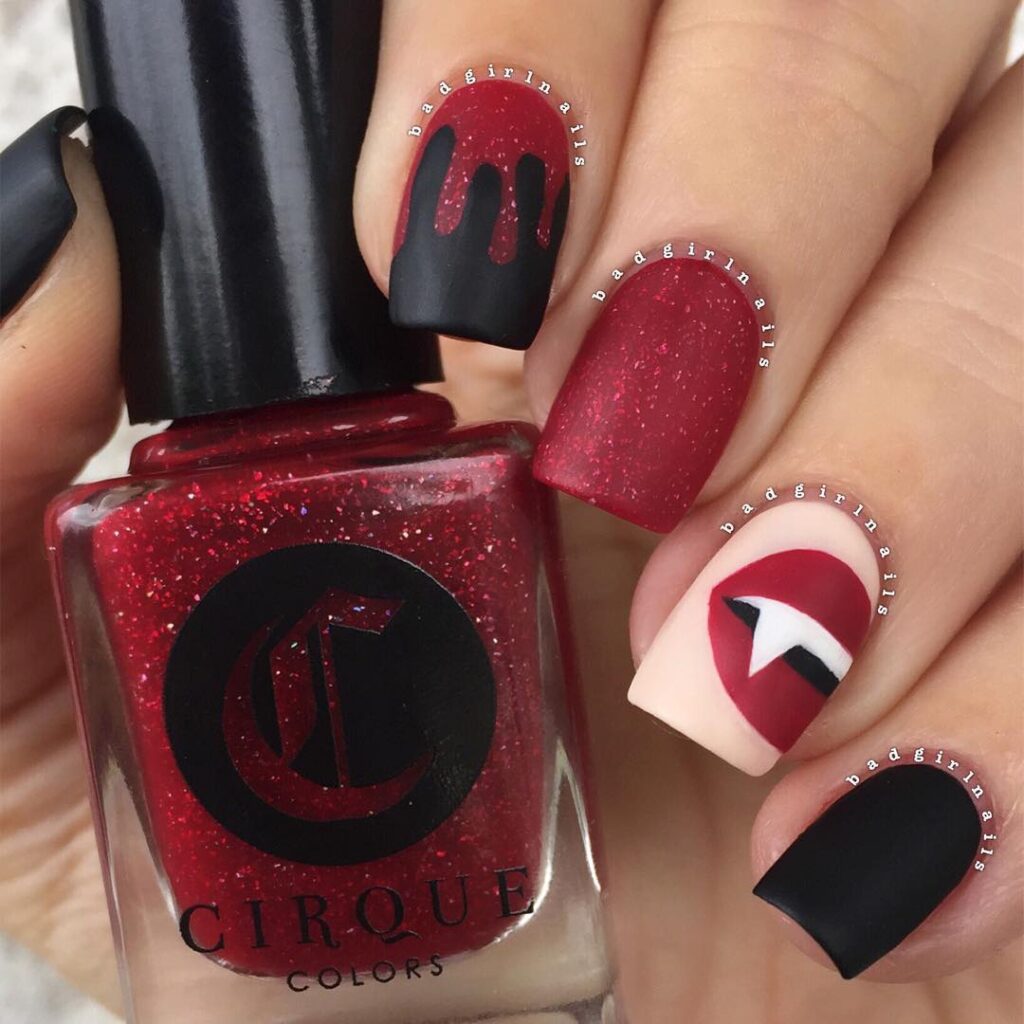 Short nails of vampire lips and dripping blood. in black and glitter red, holding red nails polish bottle.